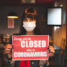 Woman holding a closing sign in a restaurant