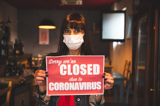 Woman holding a closing sign in a restaurant